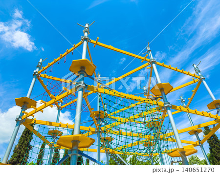Climbing structure in a park on a sunny day with bright blue sky and white clouds 140651270