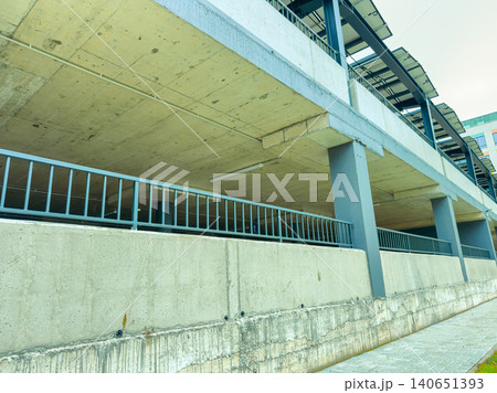 Concrete structure shows parking area under a building with multiple levels and support columns during daylight in an urban setting 140651393