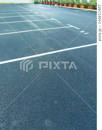 Empty parking lot with white lines and planters during daytime in a quiet area Empty parking lot with white lines and planters during daytime in a quiet area 140651407