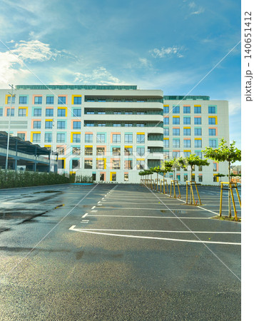 Modern office building with colorful design and empty parking lot on a bright day in a city Modern office building with colorful design and empty parking lot on a bright day in a city 140651412