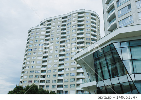 Tall apartment building in a city with a modern design near a cloudy sky during the day Tall apartment building in a city with a modern design near a cloudy sky during the day 140651547