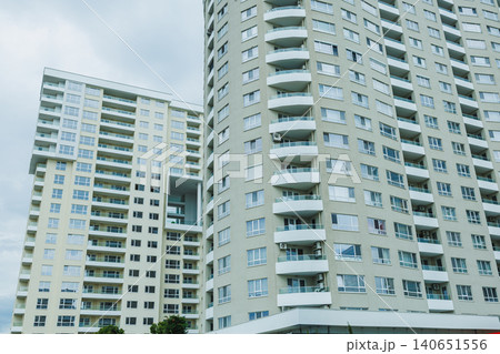 Large modern apartment buildings in an urban area under a cloudy sky with multiple balconies visible on each floor Large modern apartment buildings in an urban area under a cloudy sky with multiple balconies visible on each floor 140651556
