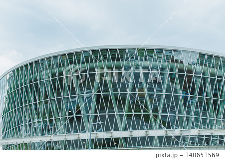 Modern building with geometric glass design in a cloudy sky Modern building with geometric glass design in a cloudy sky 140651569
