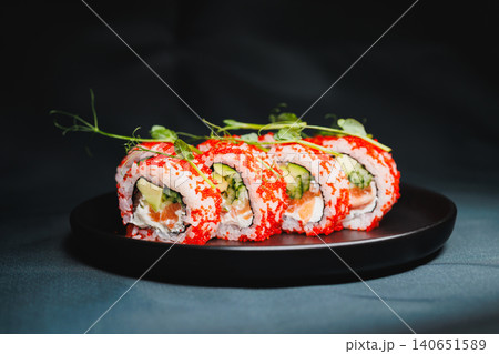 Fresh sushi rolls served on a black plate with bright ingredients and garnishes during a casual dining experience in a restaurant 140651589