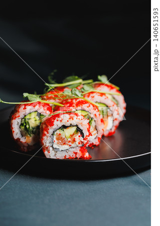 Sushi rolls with salmon, cucumber, and spicy mayo served on a black plate in a restaurant setting during a dinner time Sushi rolls with salmon, cucumber, and spicy mayo served on a black plate in a restaurant setting during a dinner time 140651593