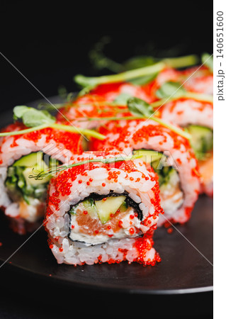 Colorful sushi rolls arranged on a black plate showcasing fresh ingredients and a vibrant look during dinner time 140651600