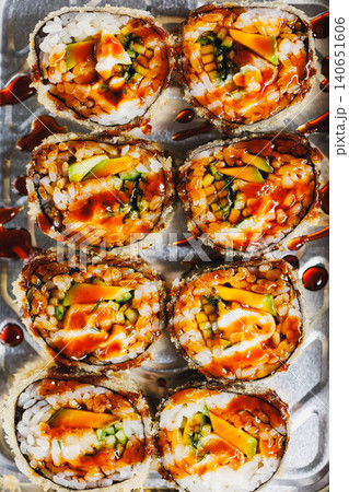 Fresh sushi rolls are served on a metal tray with sauce on top during dinner time at a local restaurant in the city 140651606