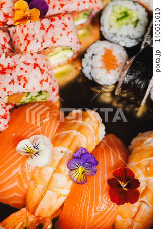 Sushi platter with salmon, colorful rolls, and edible flowers served on a plate during a dining experience Sushi platter with salmon, colorful rolls, and edible flowers served on a plate during a dining experience 140651610