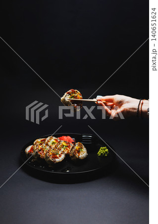 Grilled meat served on a black plate with chopsticks for a meal in a dark setting during evening hours 140651624