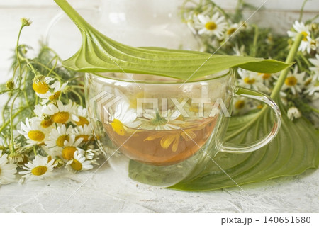 Fresh chamomile tea in a teapot and cup with flowers. Soothing chamomile tea with natural ingredients. Fresh chamomile tea in a teapot and cup with flowers. Soothing chamomile tea with natural ingredients. 140651680