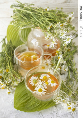 Fresh chamomile tea in a teapot and cup with flowers. Soothing chamomile tea with natural ingredients. Fresh chamomile tea in a teapot and cup with flowers. Soothing chamomile tea with natural ingredients. 140651681