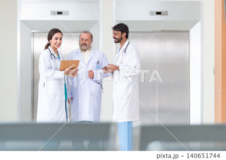 Concentrated male and female doctors in white medical uniforms look at clipboards and discuss patient anamnesis together. team brainstorming make decision concept. 140651744