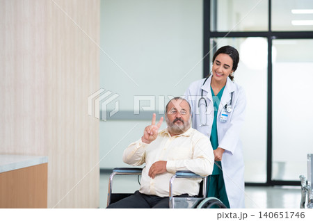 Young woman doctor with senior man sitting on wheelchair in hospital. female doctor assist take care of smiling old man. elderly healthcare concept. Young woman doctor with senior man sitting on wheelchair in hospital. female doctor assist take care of smiling old man. elderly healthcare concept. 140651746