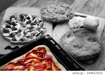 Homemade pizza preparation with fresh ingredients on wooden table 140652910