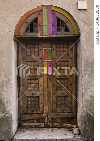 Ancient wooden door with colorful painted details and arched frame 140652930