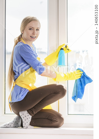 Woman cleaning window at home Woman cleaning window at home 140653100