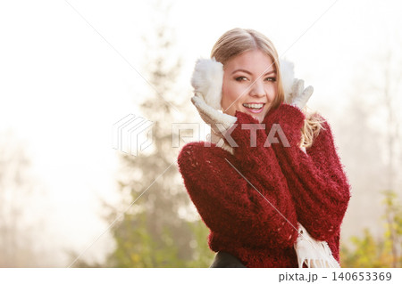 Portrait of pretty smiling woman in white earmuffs. 140653369