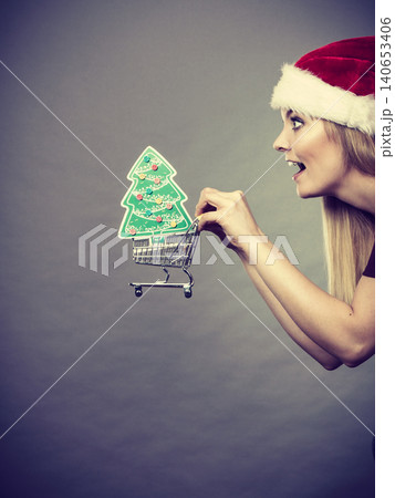 Santa woman holding shopping cart with christmas gifts Santa woman holding shopping cart with christmas gifts 140653406