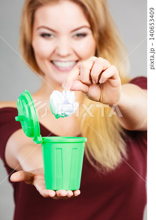 Woman putting paper into small trash can Woman putting paper into small trash can 140653409