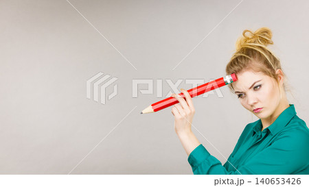 Woman confused thinking, big pencil in hand Woman confused thinking, big pencil in hand 140653426
