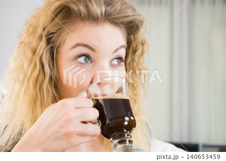 Positive woman drinking her morning coffee Positive woman drinking her morning coffee 140653459