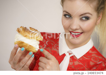 Smiling woman holds cream puff cake Smiling woman holds cream puff cake 140653474