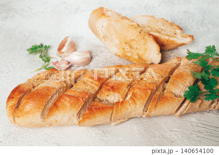 garlic bread,baguette with garlic butter and herbs, on a light table, top view, garlic bread,baguette with garlic butter and herbs, on a light table, top view, 140654100