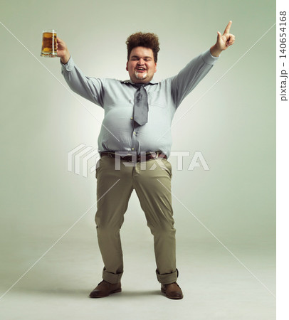 Happy man, portrait and celebration with beer for party or obesity on a studio background. Young male person or plus size model with glass, mug or alcohol in satisfaction for booze on mockup space 140654168