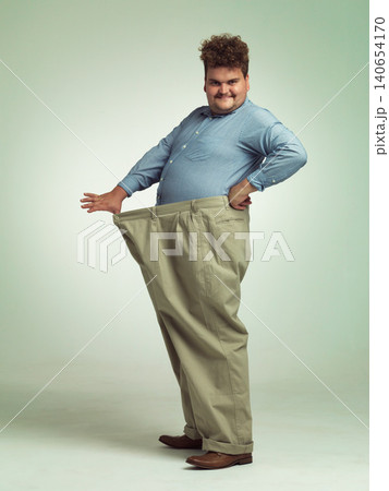 Happy man, portrait and plus size with weight loss or pants for measurement or waist on a studio background. Male person with smile for healthy diet, obesity or overweight in clothing on mockup space 140654170