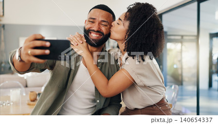 Happy couple, kiss and selfie in home with cellphone, hug and bonding on weekend together with love. Man, woman and profile picture to post on social media, romantic and funny face in living room Happy couple, kiss and selfie in home with cellphone, hug and bonding on weekend together with love. Man, woman and profile picture to post on social media, romantic and funny face in living room 140654337
