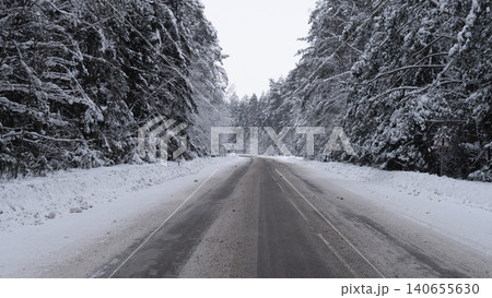 Icy Winter Road. Frozen Highway With Caution Advised. Slippery Winter Street With Snow And Ice Covering Pavement. Dark Rainy Road Lined With Snow And Ice During Cold Winter Nights 140655630