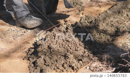 Boots Next To Fresh Mortar Pile On Sandy Site, Showing Work Pause And Gritty Texture Of Building Materials With Nearby Tools And Footprints Indicating Active Masonry Task. 140655783
