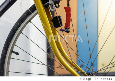 A detailed close up shot of a bicycle front wheel featuring a bright yellow fork and silver spokes, High Quality Photo 140656343