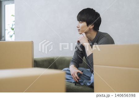 段ボール箱に囲まれて座る若い男性　引っ越し　イメージ 140656398