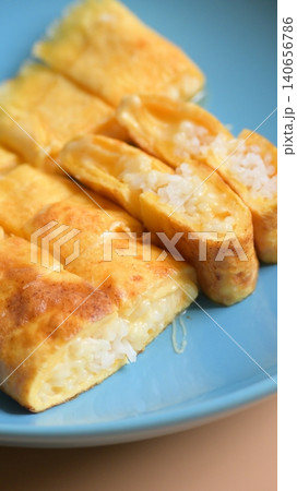 roll omelette stuffed with chesse and rice on blue plate, delicious food in the morning roll omelette stuffed with chesse and rice on blue plate, delicious food in the morning 140656786