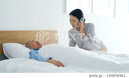 昏睡するシニア男性とスマホで電話する女性 140656961