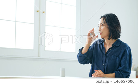 部屋で水を飲むミドル女性 部屋で水を飲むミドル女性 140657006