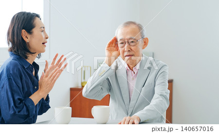 耳の遠いシニア男性と会話するミドル女性 耳の遠いシニア男性と会話するミドル女性 140657016