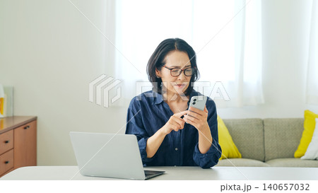 スマホを見ながら悩むミドル女性 スマホを見ながら悩むミドル女性 140657032