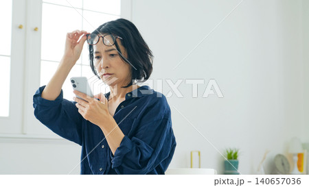 スマホを見ながら悩むミドル女性 スマホを見ながら悩むミドル女性 140657036