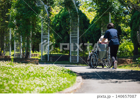 車椅子での散歩する高齢者とヘルパー 車椅子での散歩する高齢者とヘルパー 140657087