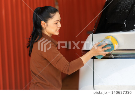 woman washing car with sponge and foam in a self-service car wash station 140657350