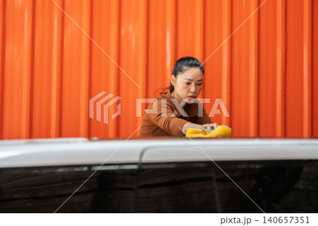 woman washing car with sponge and foam in a self-service car wash station woman washing car with sponge and foam in a self-service car wash station 140657351