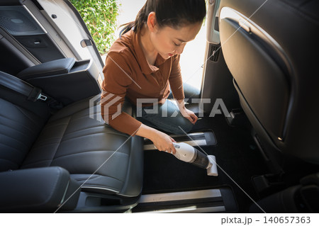 woman using portable handheld vacuum cleaner to cleaning the floor mat of her luxury car woman using portable handheld vacuum cleaner to cleaning the floor mat of her luxury car 140657363