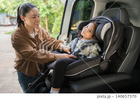 mother is fastening safety belt to preschool child girl in car seat, safety baby chair travelling mother is fastening safety belt to preschool child girl in car seat, safety baby chair travelling 140657370