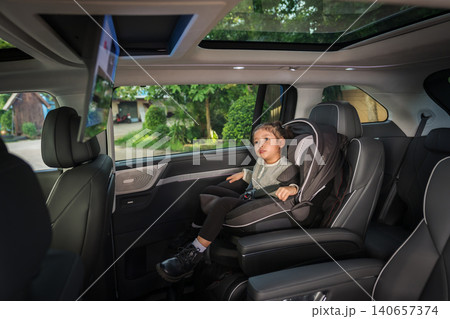 preschool child girl watching rear entertainment screen or ceiling screen while sitting in car seat, safety baby chair travelling preschool child girl watching rear entertainment screen or ceiling screen while sitting in car seat, safety baby chair travelling 140657374