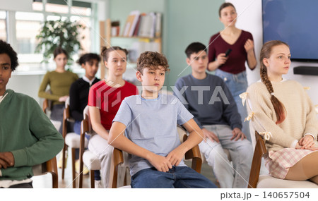 Teenage students listening to lecture while teacher stands in background Teenage students listening to lecture while teacher stands in background 140657504