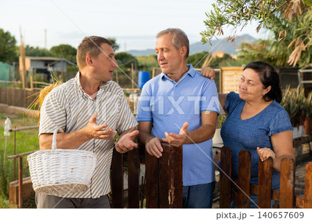 Man talking with neighbours near backyard garden Man talking with neighbours near backyard garden 140657609