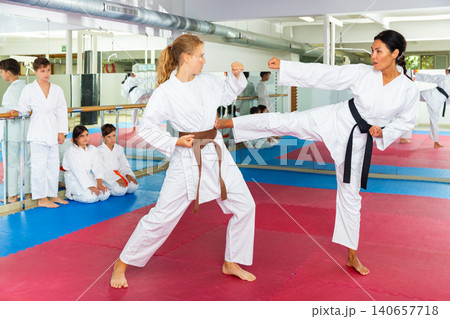 Female trainer teaches teen girl karate kicks at workout in sport gym 140657718