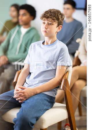 Teenage boy listening to teacher while sitting with classmates in classroom 140657993